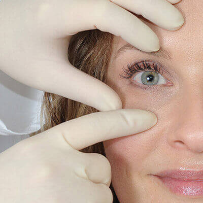 Woman Having an Eye Inspected By a Person With Gloves